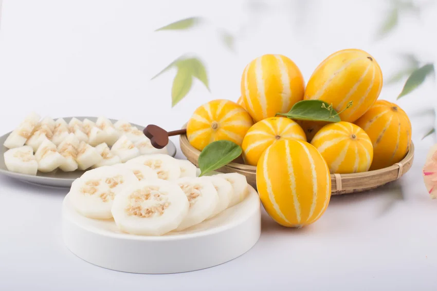 하얀 접시 위에 동그랗게 썰어 놓은 참외 조각들과 뒤편 바구니에 담긴 통참외들