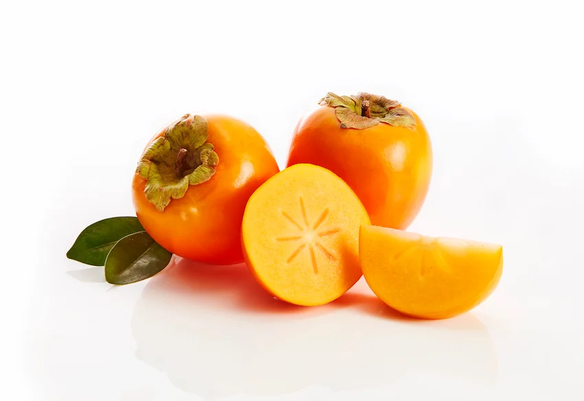 단감, 깨끗한 흰 배경 위에 놓인 매끈한 단감 두 알과 별 모양의 중심이 선명한 단감 단면 및 조각의 모습